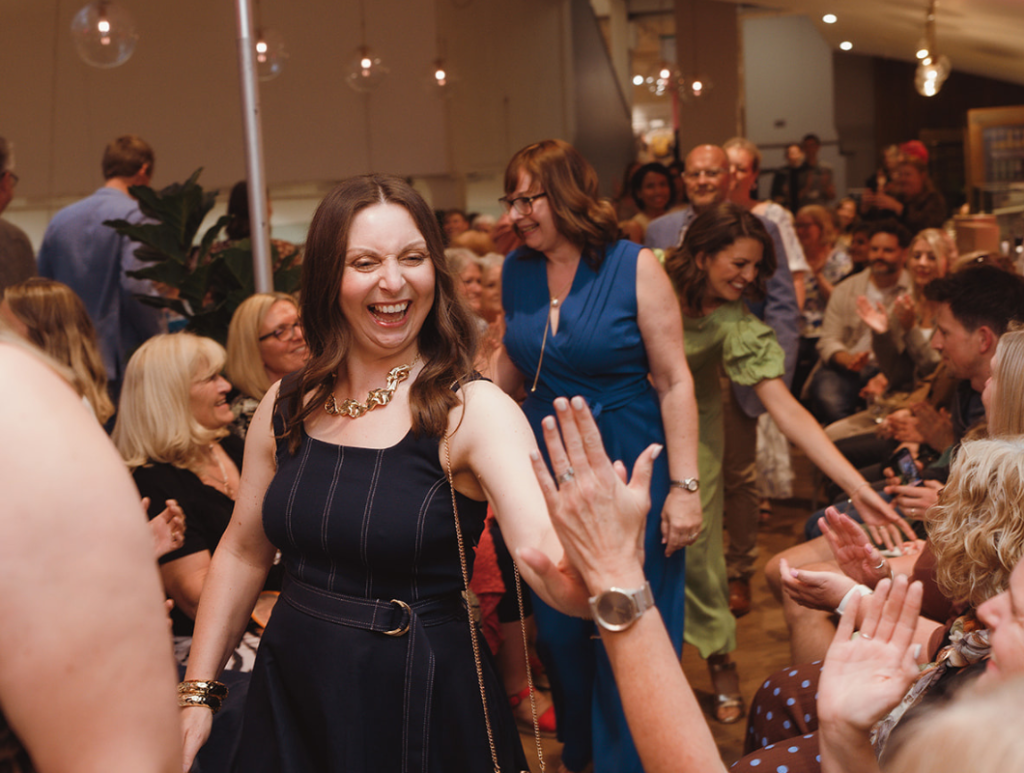 Beneficiaries high five audience on the runway