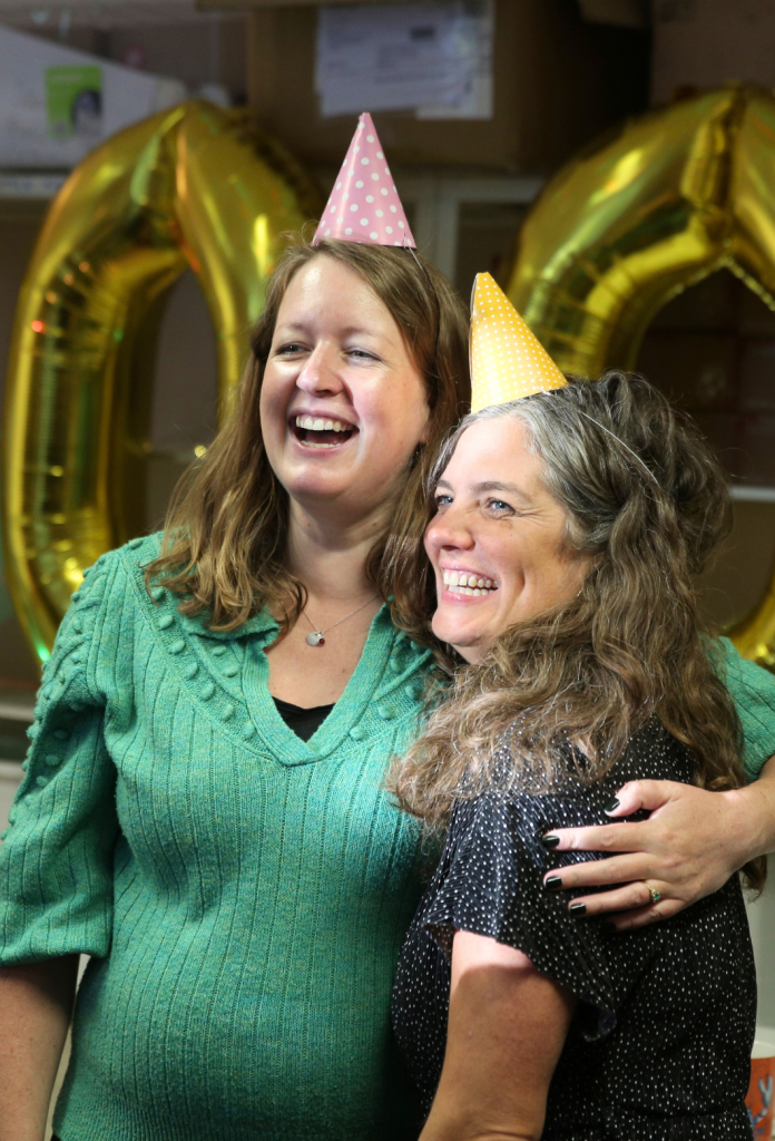 Lizzie and Kay smiling in party hats, little lifts 50000th box party