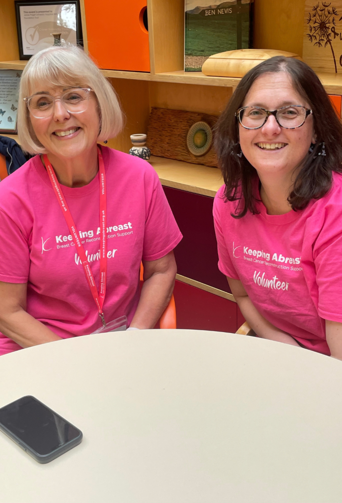 Two keeping abreast volunteers sitting at the table smiling