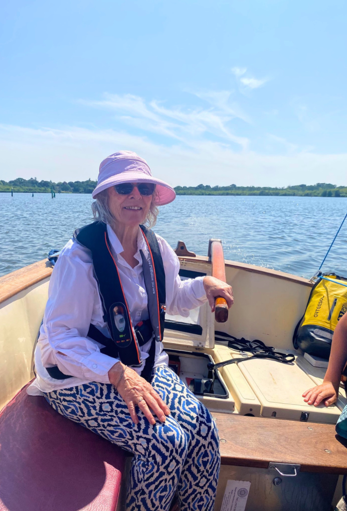 A Little Lifts community member steering the sailing boat on the Norfolk Broads
