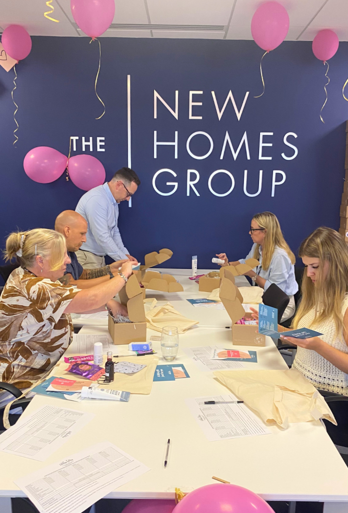 New Homes Group staff packing Little Lifts breast cancer care boxes at their office.
