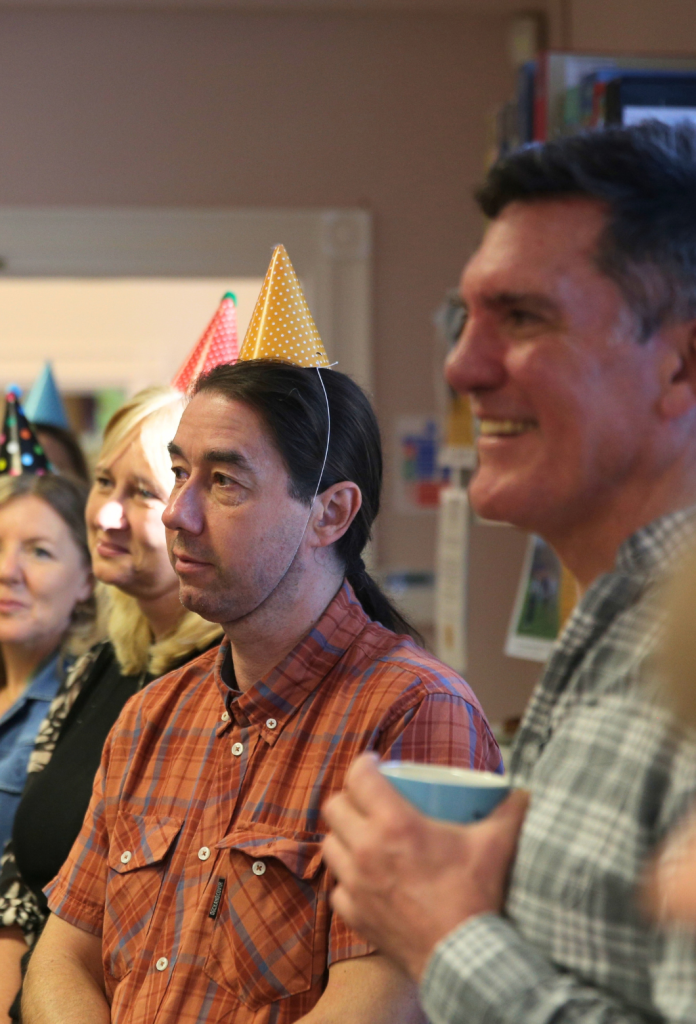 two men smiling in party hats
